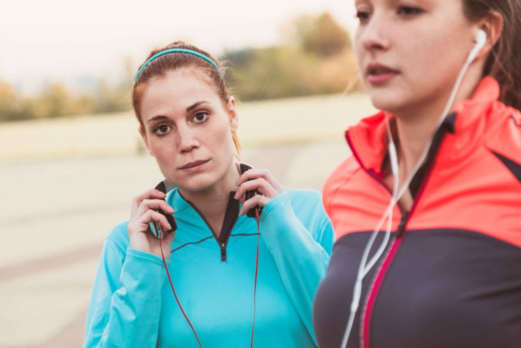 concentrated-sportswoman-with-hands-headphones_11zon A focused woman adjusting her headphones while preparing for an outdoor workout.