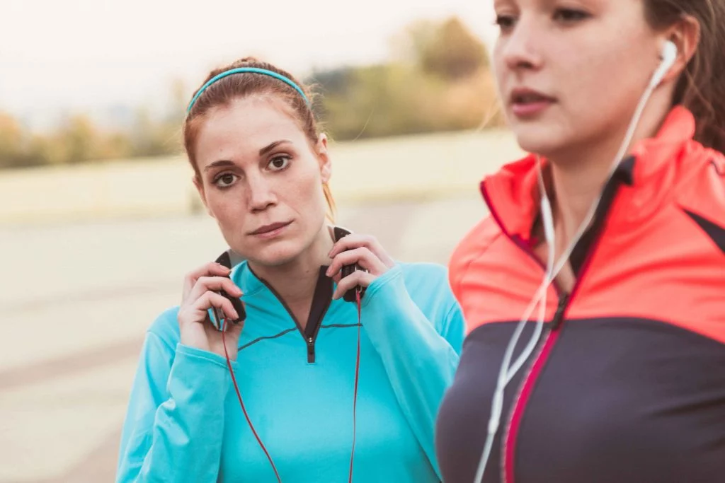 A focused woman adjusting her headphones while preparing for an outdoor workout.