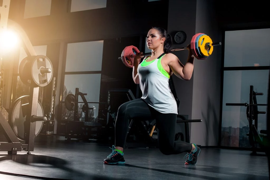Woman doing weighted lunges to build muscle and burn fat simultaneously.