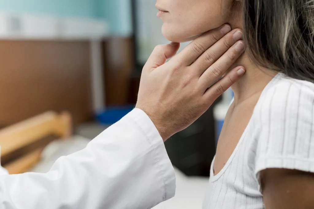 Doctor checking woman's thyroid for possible hyperthyroidism and weight issues.