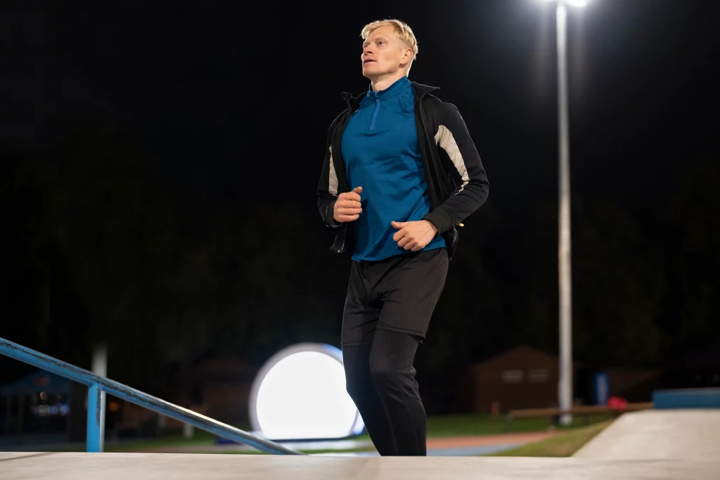 Man jogging at night in sportswear under bright streetlights