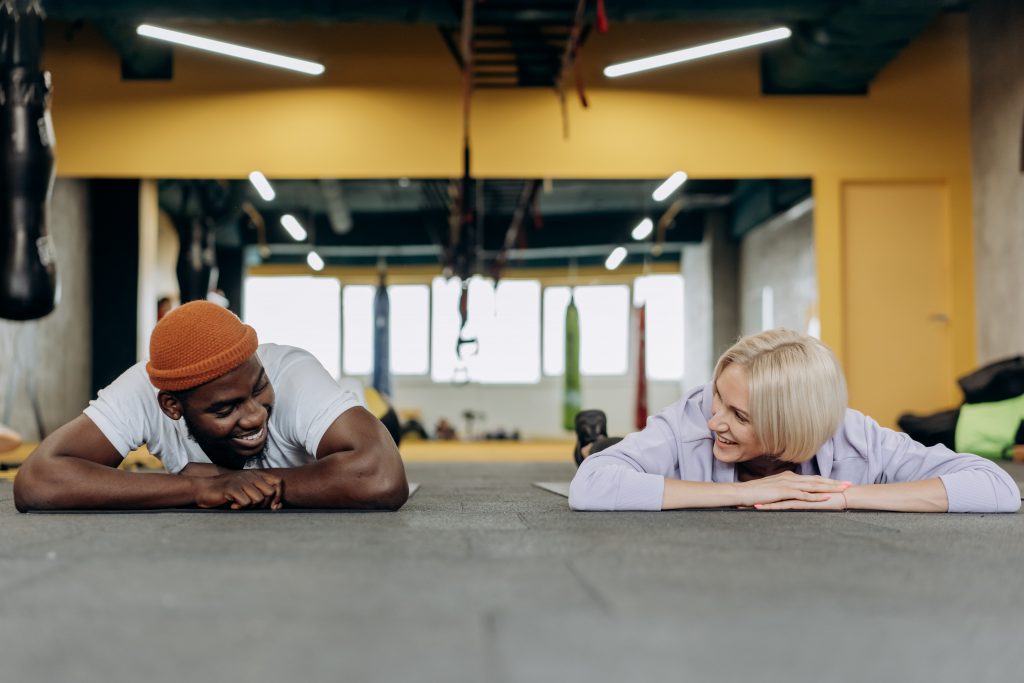 a personal trainer and the trainee are exercising and smiling