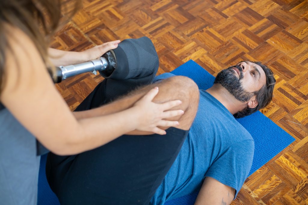 The personal trainer keeps trainee's knees to complete his movement