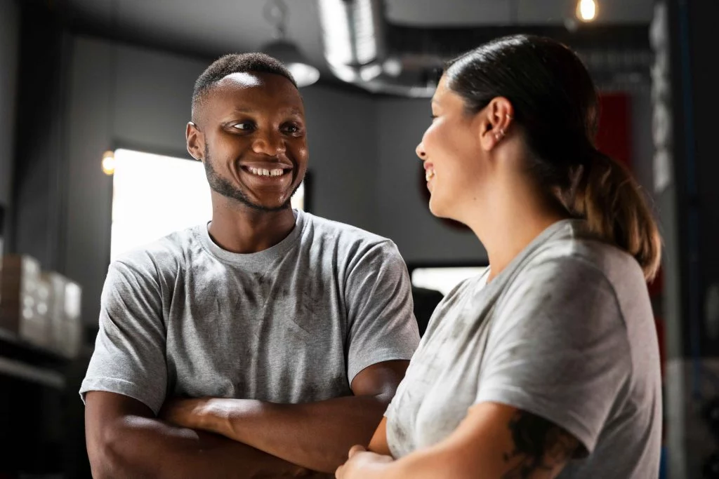 Personal trainers happy sharing insights in a bright training space.