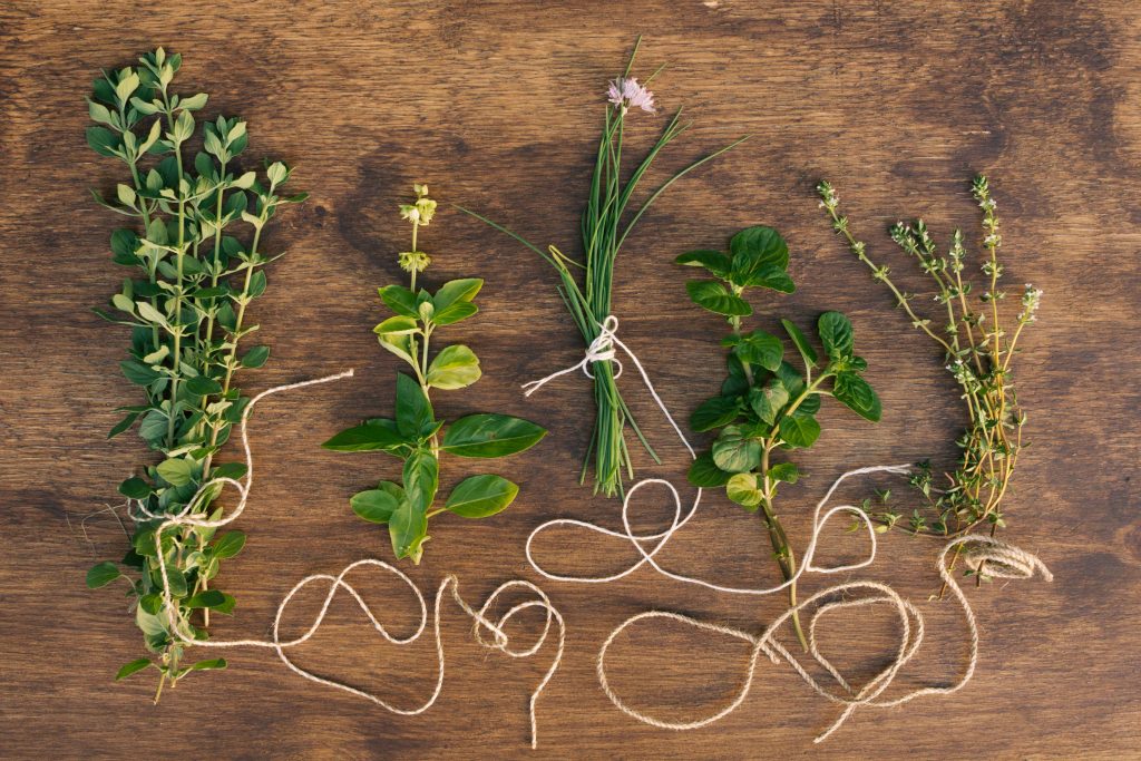 collection-green-plant-twigs_11zon Five fresh herb bundles tied with twine on a rustic wooden table, showcasing common Marjoram Substitutes.