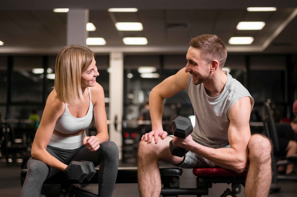man-woman-working-out-together_11zon Personal trainers happy exercising together with dumbbells in a gym.