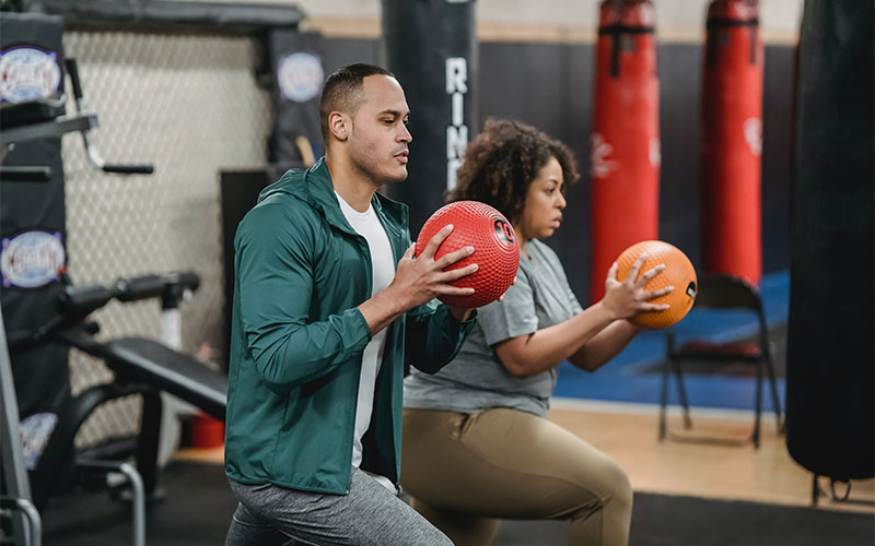 second The trainer and trainee are exercising with two balls