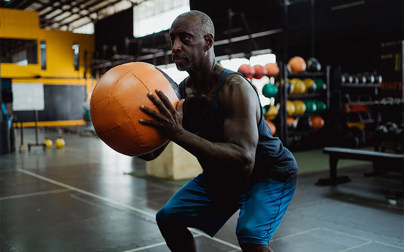 A male senior is exercising with an exercise ball