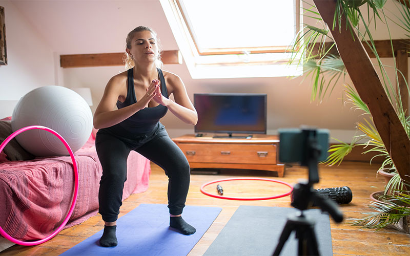 A trainer is stretching herself and teaching in an online class