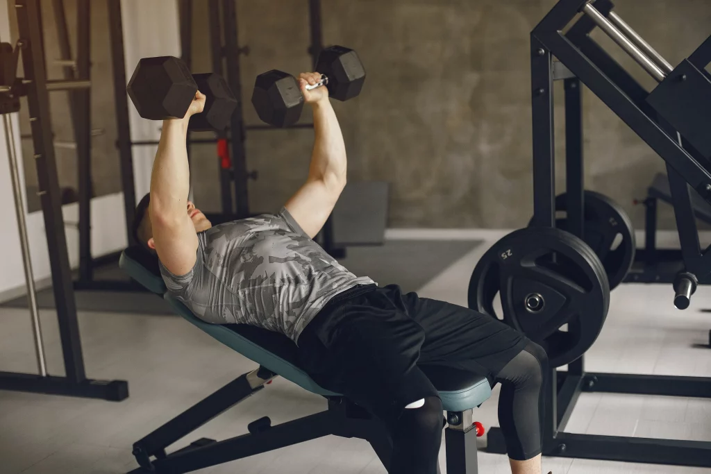 A man performing incline dumbbell flye on a bench to isolate the upper chest muscles during a chest isolation workout.