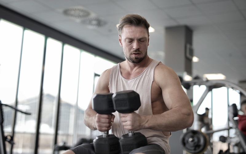A man is exercising with heavy dumbbells at the gym 