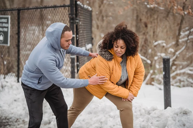A personal coach is helping the trainee do the workout.