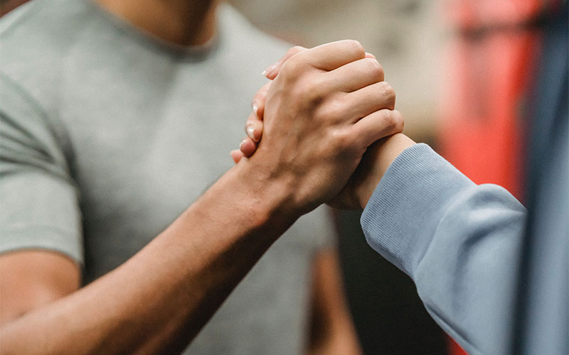 The trainer is encouraging the trainee by shaking hand