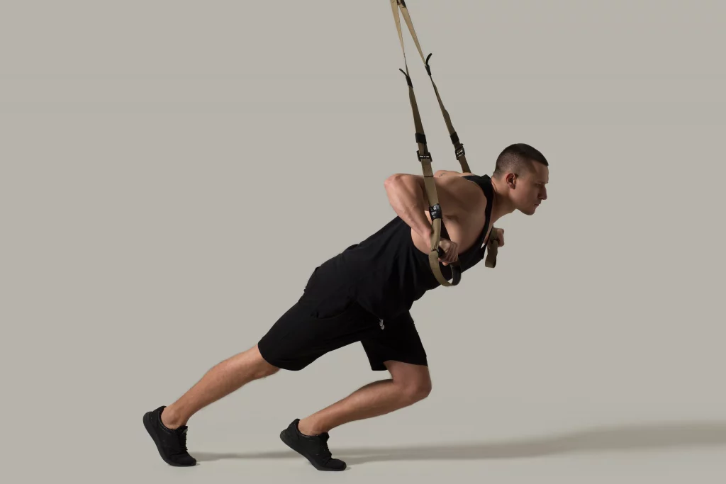 A man performing a bodyweight chest fly using suspension straps as part of chest isolation exercises to strengthen and tone the pectoral muscles.