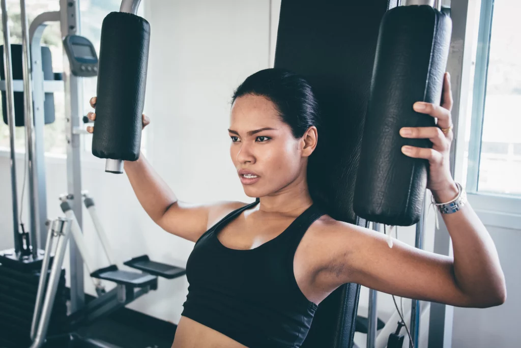 A woman performing the butterfly machine pec deck, a chest isolation exercise that targets the middle and inner pectoral muscles for better chest definition.