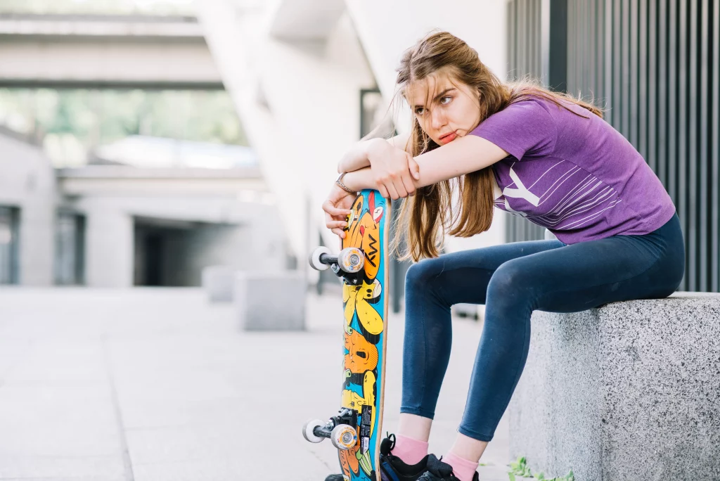 athletic-girl-is-leaning-her-colorful-skateboard_3 A teenage girl is taking a break from skateboarding, leaning on her colorful skateboard.