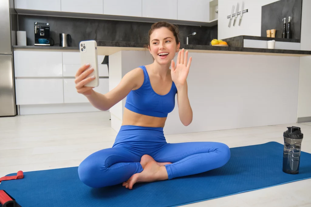 A woman greeting her online yoga instructor during a virtual session designed for beginners.