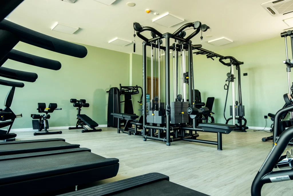 Bright, empty gym with treadmills and multi-station weight machines in a clean, modern workout space.
