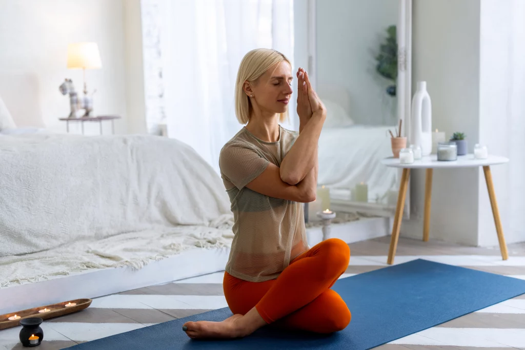 full-shot-woman-doing-yoga-mat Woman practicing online yoga classes at home in a calm, minimalist living space.