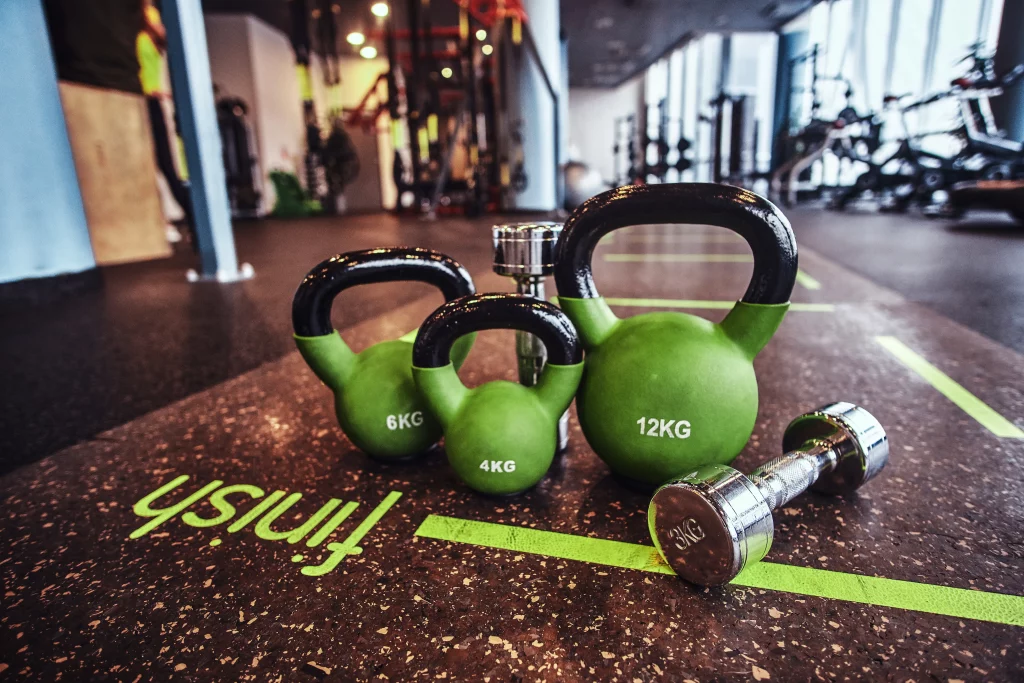 Kettlebells and dumbbells are on the floor of a strength area in the best gyms in Los Angeles.