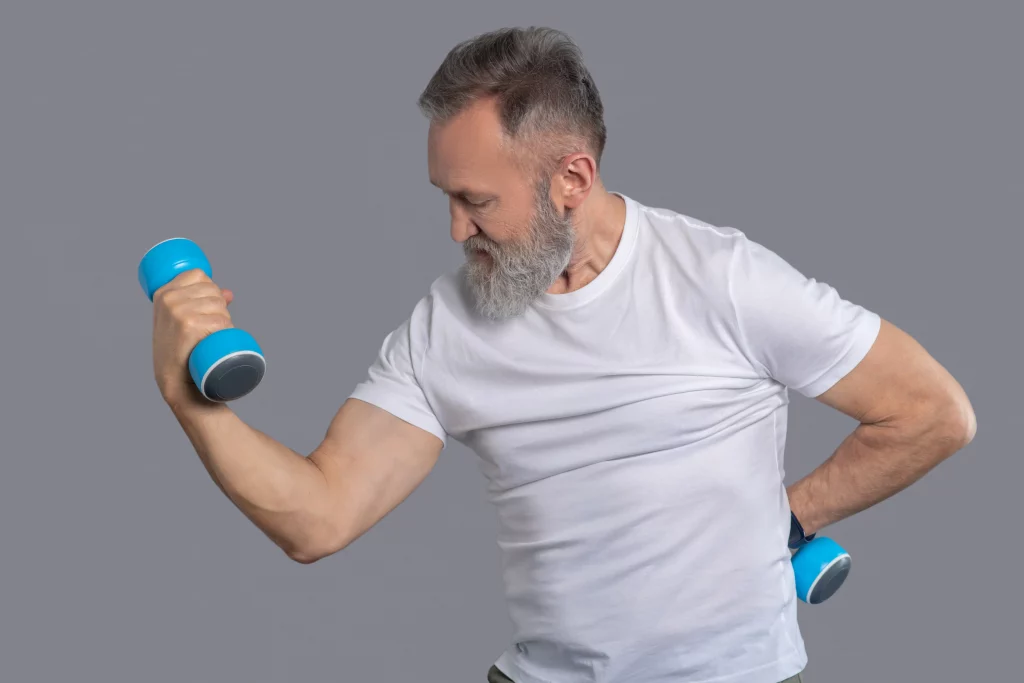 A man over 40 performing a controlled dumbbell workout during an online fitness coaching session.