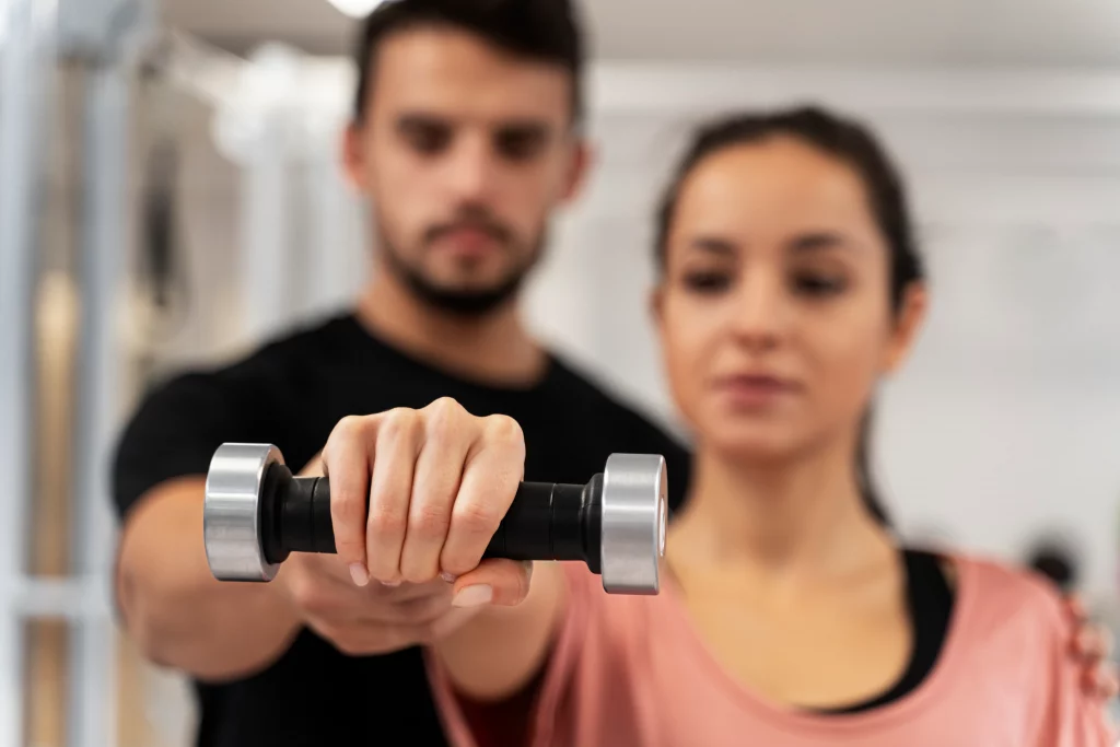 Personal trainer in Vancouver demonstrating dumbbell exercise form with client during in-person training session.
