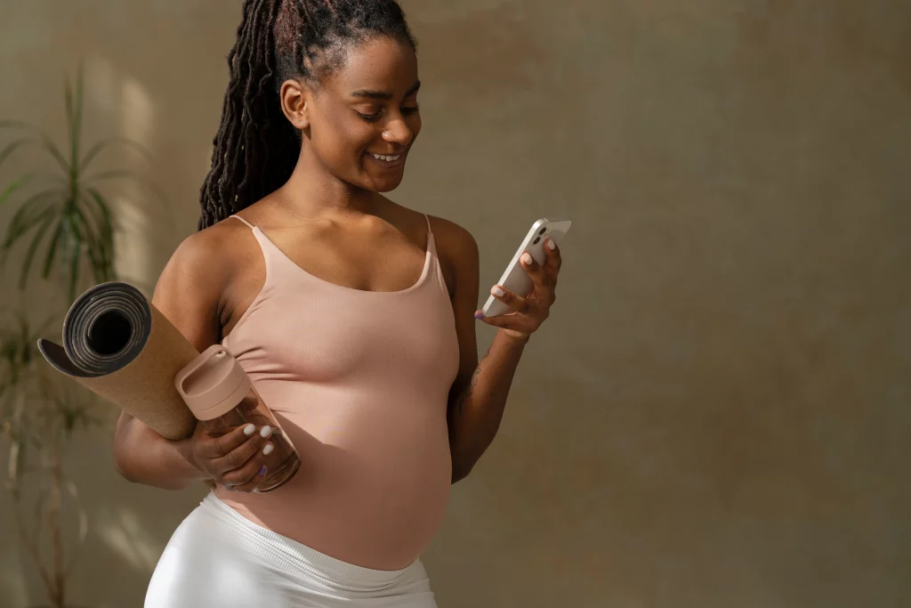 medium-shot-pregnant-woman-holding-yoga-mat An expectant mother browsing the best workout apps for women on her phone