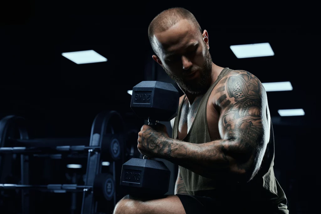 Personal Trainers for Bodybuilding coach lifting a 20kg dumbbell during an intense gym strength training session.