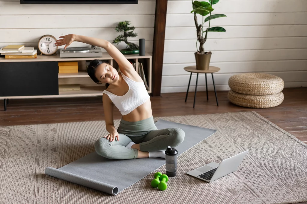 Home workout vs gym comparison showing a woman exercising in a living room with simple fitness equipment