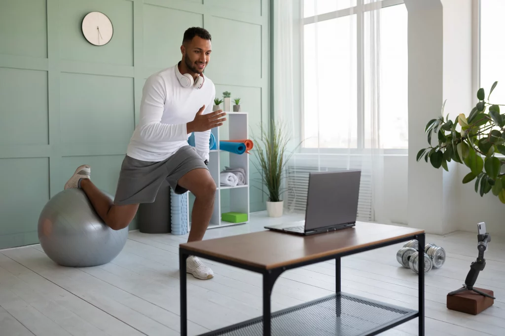 full-shot-smiley-man-training-with-gym-ball A man exercising at home with an online personal trainer in Vancouver through a live video call