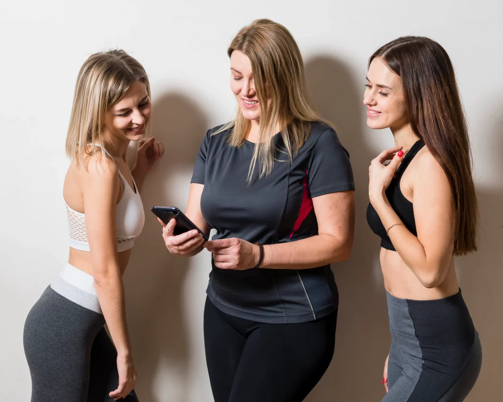 group-women-relaxing-gym Fitness coach talking with young women about exercise as part of online weight loss coaching for teens.